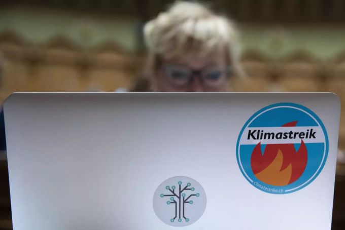 Aline Trede, Fraktionschefin der Grünen und Berner Nationalrätin, arbeitet an ihrem Laptop, welcher mit einem Aufkleber des Klimastreiks versehen ist. Trede Grüne Klimastreik Parlament