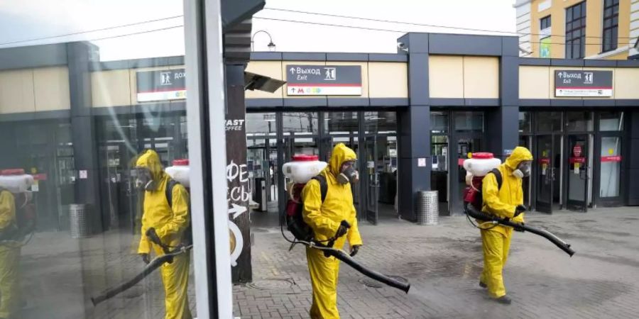 Mitarbeiter des Katastrophenschutzes desinfizieren einen Bahnsteig in Moskau. Foto: Alexander Zemlianichenko/AP/dpa