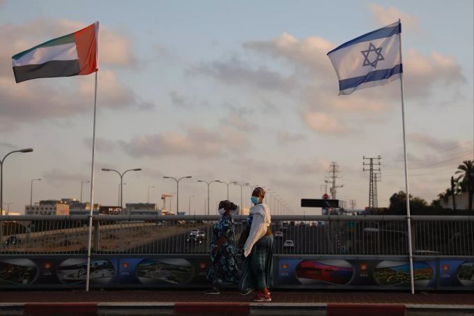 Frauen mit Schutzmasken gehen an den Flaggen von Israel und den Vereinigten Arabischen Emiraten auf der Friedensbrücke vorbei. Nach der angekündigten Normalisierung ihrer Beziehungen steuern Israel und die Vereinigten Arabischen Emirate in schnellen Schritten auf einen regelmässigen diplomatischen Kontakt zu. Israel und Emirate