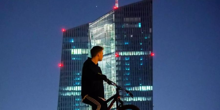 Ein junger Mann steht mit seinem Rad vor dem EZB-Tower. Europas Währungshüter stemmen sich mit Milliarden gegen die beispiellose Konjunkturkrise infolge der Corona-Pandemie. Foto: Andreas Arnold/dpa