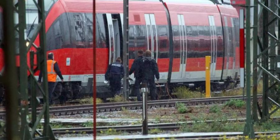 Mitarbeiter der Polizei stehen bei einem Zug auf dem Gelände des DB Betriebsbahnhofs Deutzer Feld. Hier wurde das verdächtige Paket in einem abgestellten Zug entdeckt. Foto: Steil-TV/dpa