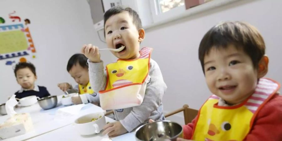 Kleinkinder beim Mittagessen in der Kindertagesstätte «Magic International Daycare». Foto: How Hwee Young/epa/dpa