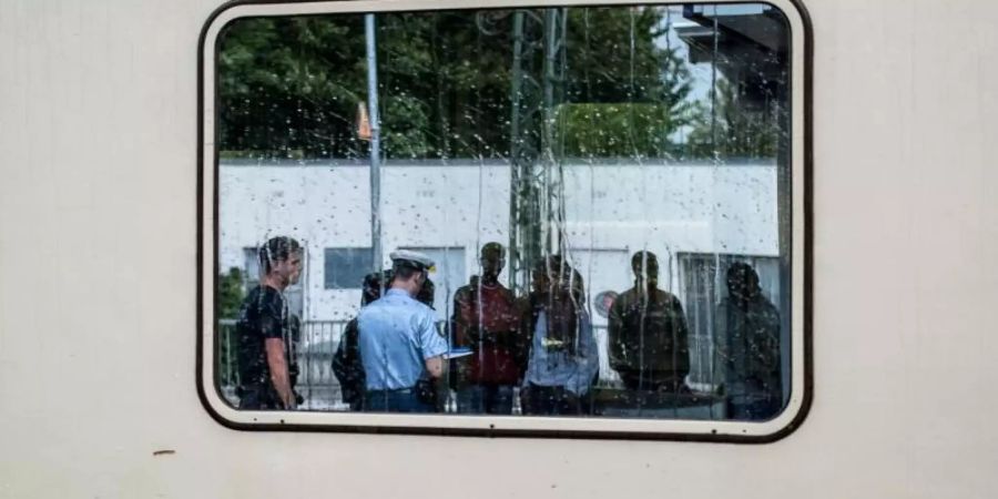 Zwei Bundespolizisten nehmen auf einem Bahnhof in Bayern die Personalien von im Zug aufgegriffenen Flüchtlingen auf. Foto: Nicolas Armer/dpa/Archiv