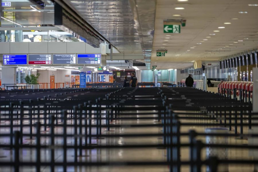 Security-Personal läuft am 24.März am menschenleeren Flughafen Genf beim Check-In des Terminal 1 herum.