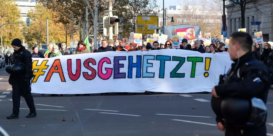 Teilnehmer einer Demonstration gehen mit einem Transparent mit der Aufschrift "#ausgehtzt!" eine Strasse in Magdeburgs Innenstadt entlang.