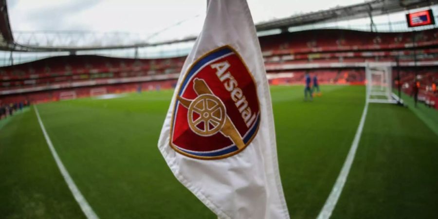 Das Logo des englischen Premier-League-Klubs FC Arsenal vor einem Fussballfeld.