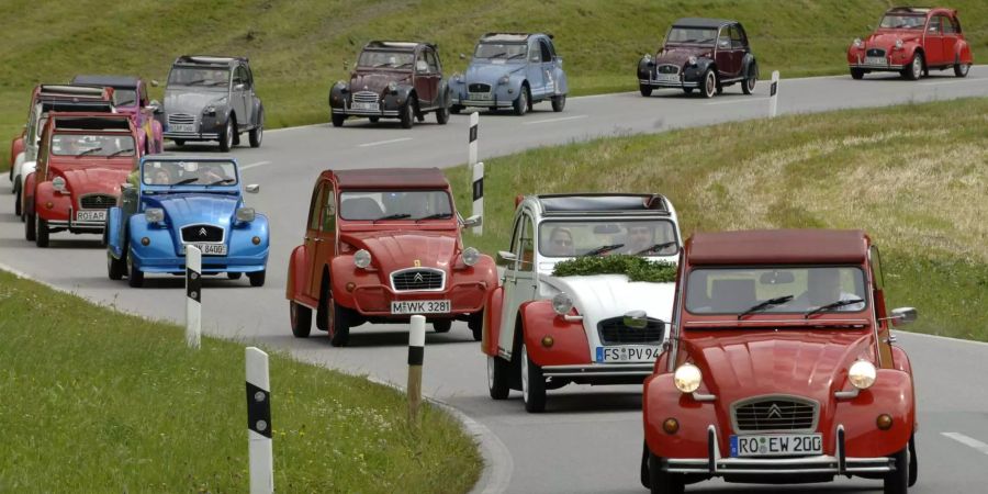 Dicht an dicht fahren diverse Citroen 2CV, die sogenannten «Enten», auf einer Strasse.