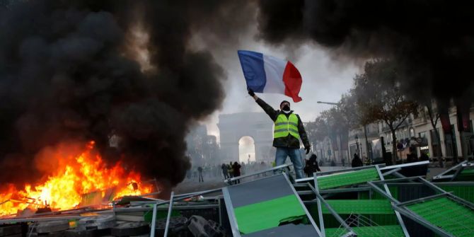 Gelbwesten-Aktivist mit französischer Flagge vor Arc de Triomphe