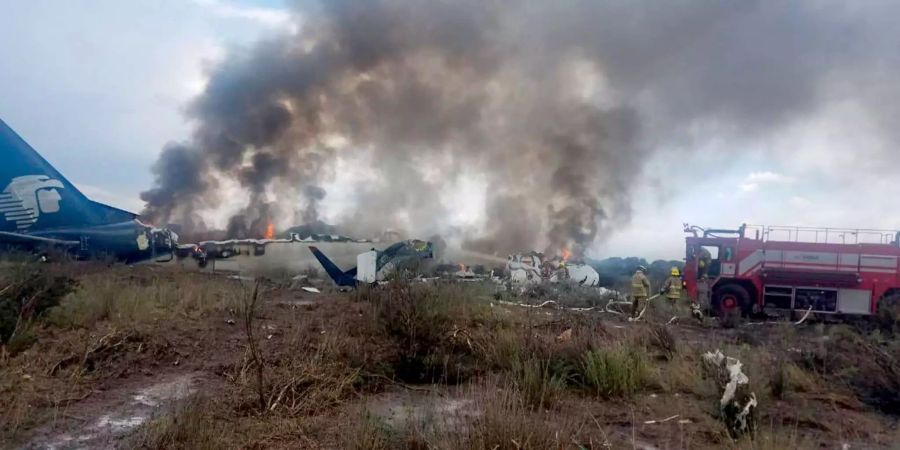 Rettungskräfte in der Nähe des rauchenden Wracks eines verunglückten Flugzeugs nahe des Flughafens Guadalupe Victoria im Bundesstaat Durangoim im Einsatz. Im Norden Mexikos ist eine Passagiermaschine verunglückt.