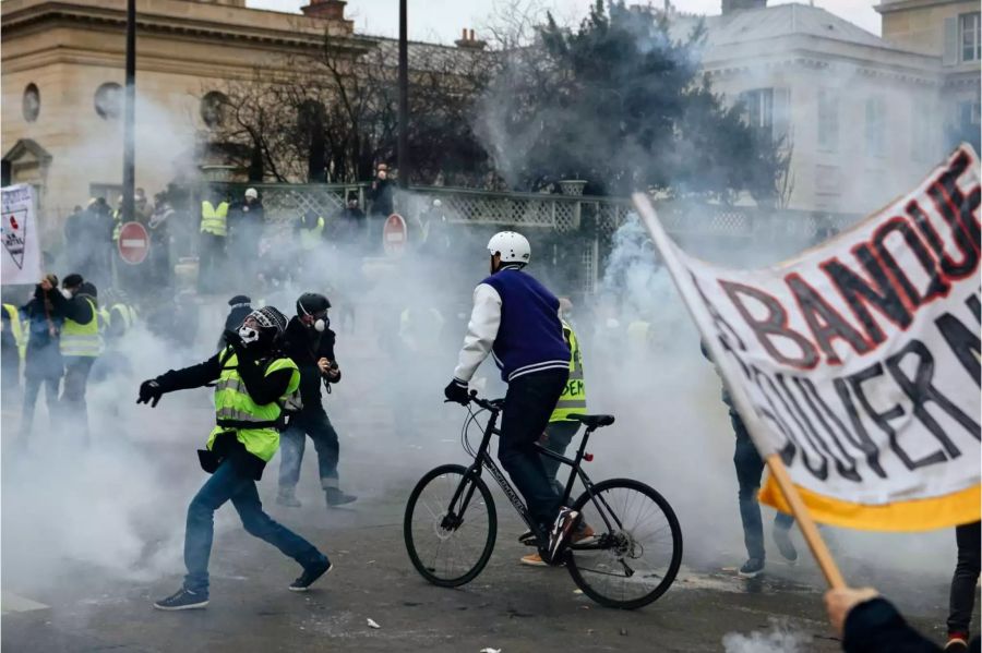 Demonstranten stehen in einer Tränengaswolke, das von Polizisten während eines «Gelbwesten»-Protests eingesetzt wurde.