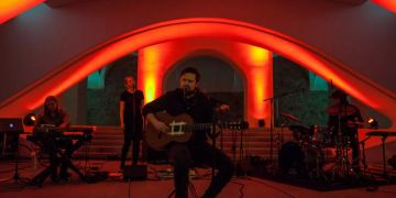 Gitarrist singt auf Bühne in Mikrofon.