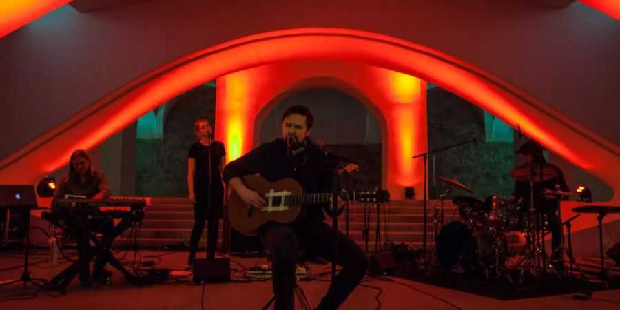 Gitarrist singt auf Bühne in Mikrofon.