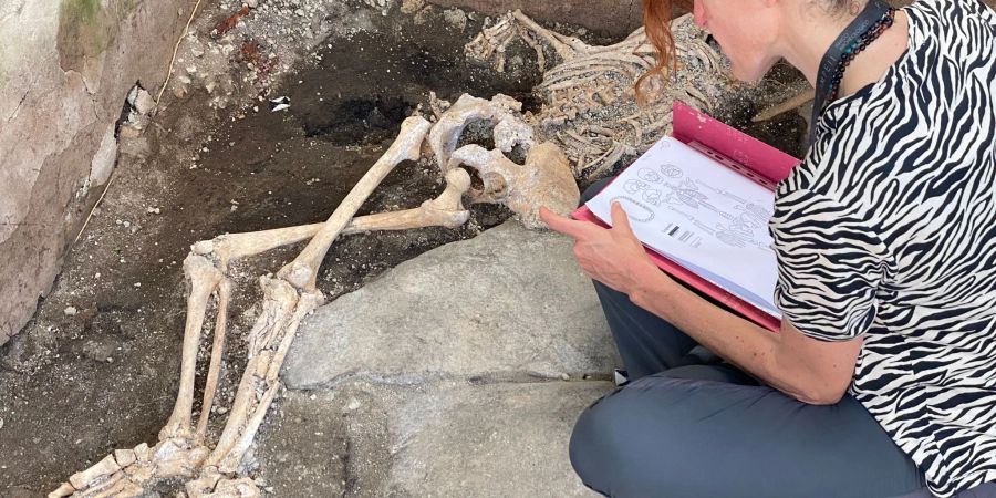 Eine Frau sitzt vor einem Skelett im Archäologiepark Pompeji.