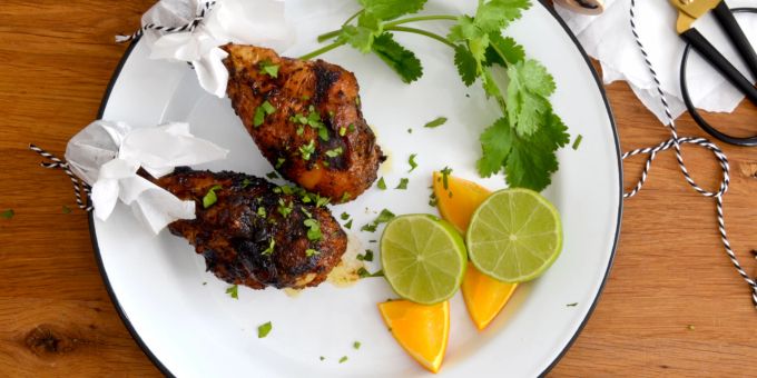 Mit Koriander garniert müssen nur noch die Zitrusfrüchte über dem Fleisch des Jerk Chicken ausgedrückt werden. Das verpasst den Keulen einen extra Frischekick. Poulet gegrillt Limette Koriander Teller weiss