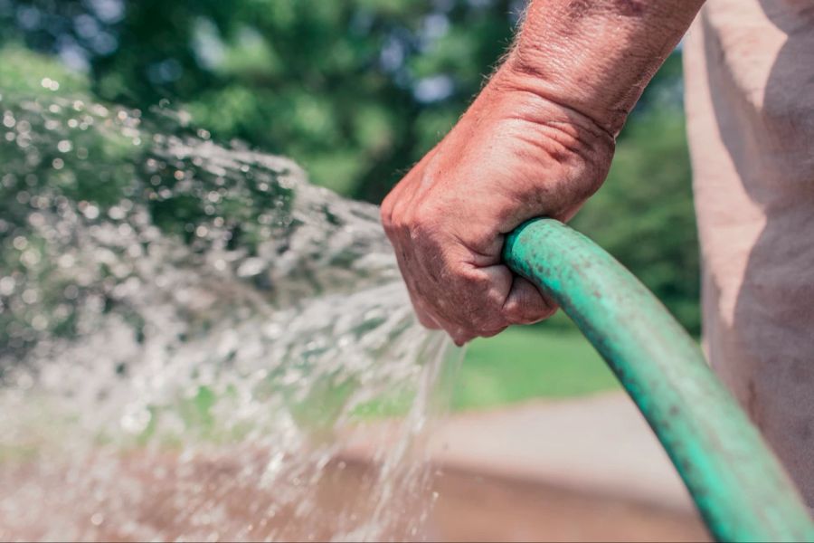 Mann hält Wasserschlauch