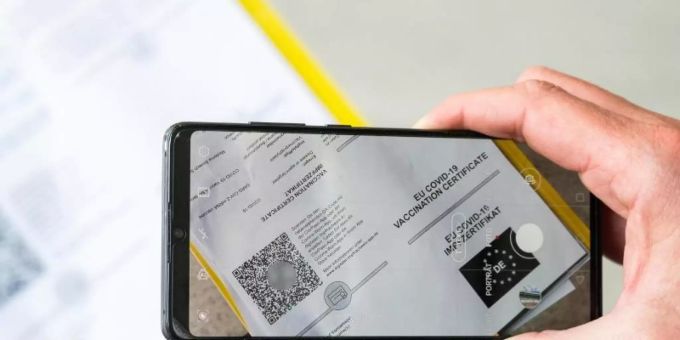 Ein Mann scannt mit einem Handy ein Dokument für den Digitalen Impfnachweis. EU-Zertifikat