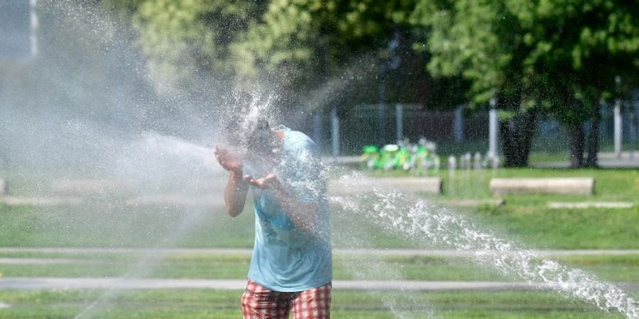 Mann in Berlin hält Kopf in Wasserstrahl