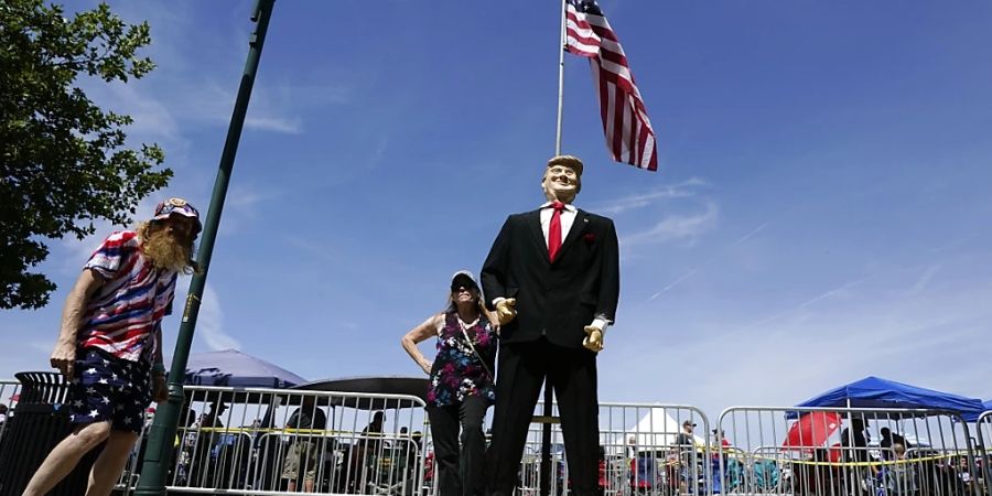 Anhänger des ehemaligen US-Präsidenten Trump halten vor einer Trump-Statue inne, Stunden vor Trumps Rede bei einer «Save America»-Kundgebung. Foto: Ross D. Franklin/AP/dpa