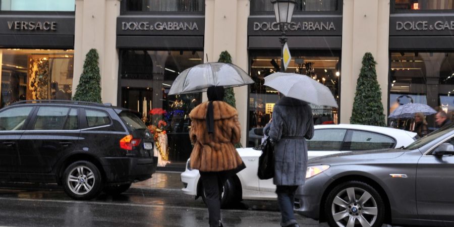 Passanten gehen auf der Maximilianstrasse in München an Luxusgeschäften vorbei.