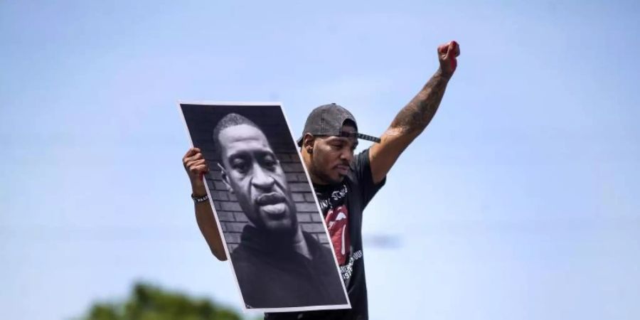 Tony L. Clark hält ein Foto des verstorbenen George Floyd. Der ehemalige Polizist Derek Chauvin ist des Mordes schulig gesprochen worden. Foto: Jerry Holt/Star Tribune/AP/dpa