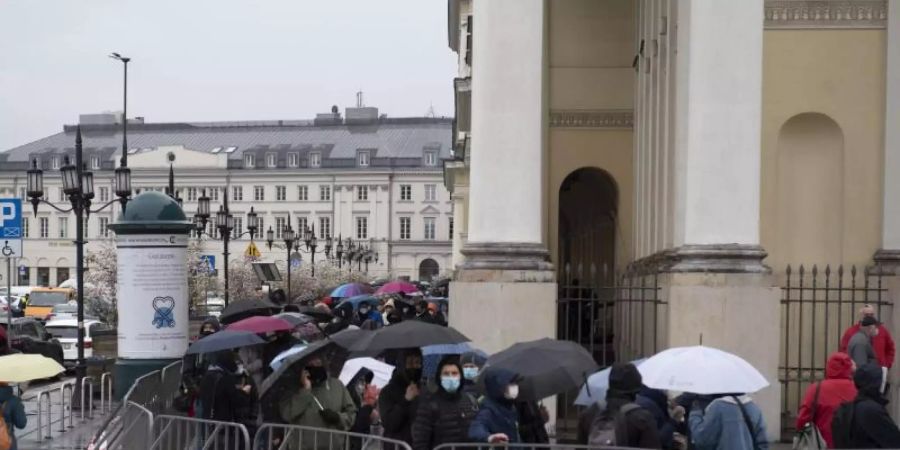 Menschen warten in einer Schlange vor dem Warschauer Rathaus auf ihre Impfung. Foto: Aleksander Kalka/ZUMA Wire/dpa