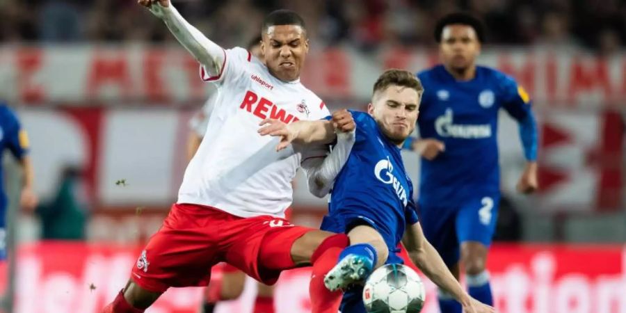 Der Kölner Ismail Jakobs (l) setzt sich im Zweikampf mit dem Schalker Jonjoe Kenny durch. Foto: Marcel Kusch/dpa