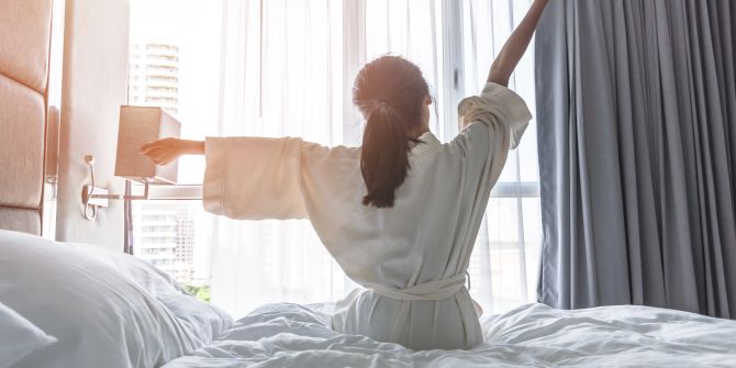 Ausgeschlafene Frau im Hotel streckt die Arme