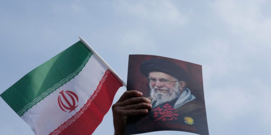 Ein Mann hält eine iranische Flagge und ein Poster des verstorbenen Obersten Führers Chamenei während einer Kundgebung zur Unterstützung seines Sohnes Ayatollah Mojtaba Chamenei, de...