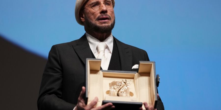 John Travolta hält seine Goldene Ehrenpalme während der 79. Internationalen Filmfestspiele. Foto: Scott A Garfitt/Invision/AP/dpa