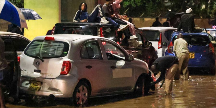 dpatopbilder - Menschen klettern auf ihre Autos, nachdem schwere Regenfälle die Straßen in Nairobi überflutet haben. Foto: Andrew Kasuku/AP/dpa
