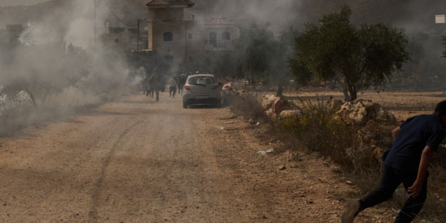 Ein palästinensischer Jugendlicher flieht vor Tränengas, das von Angehörigen der israelischen Streitkräfte nach einem Angriff von Siedlern während der Olivenernte im Dorf Abu Falah...