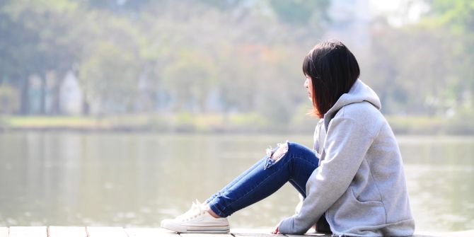 Junge Frau sitzt am Wasser