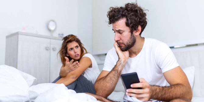 Wütende Frau stellt Mann mit Smartphone zur Rede