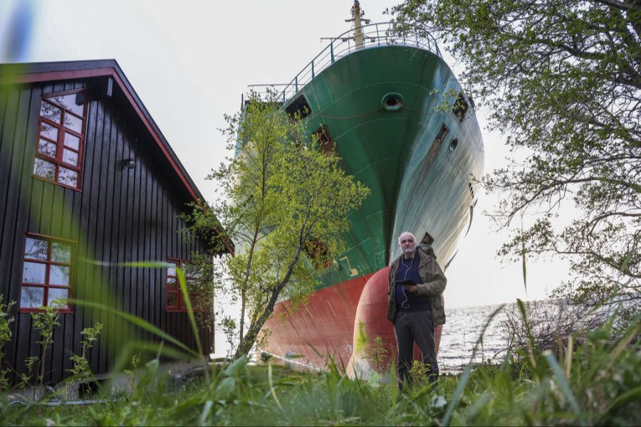 Johan Helberg steht vor seinem Haus und dem gestrandeten Containerschiff.