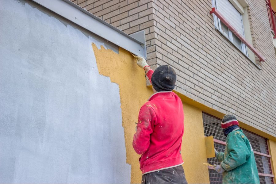 Männer streichen Hausfassade