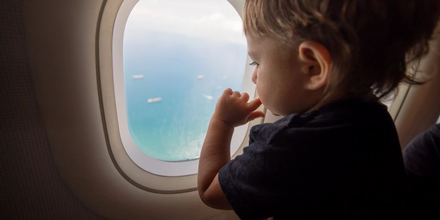 kleinkind sitzt am flugzeugfenster