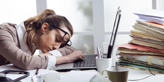 Frau schläft während der Arbeit an ihrem Laptop ein.