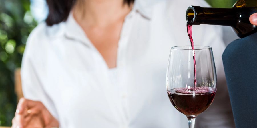 mann schenkt rotwein ein