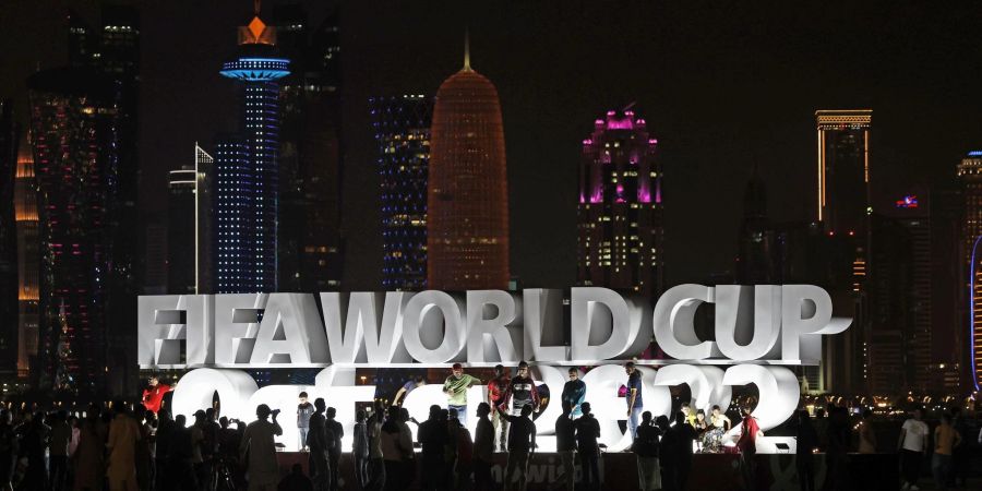 Menschen stehen vor der Eröffnung der WM vor einem beleuchteten Schriftzug «Fifa World Cup Qatar 2022».