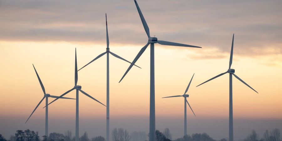 Windkraftanlagen stehen bei winterlichem Wetter nahe des Ortsteils Oldenbrok in Övelgönne vor dem Abendhimmel.