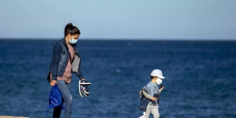 Eine Frau und ihr Sohn an einem Strand in der Nähe von Barcelona in Spanien. Foto: Emilio Morenatti/AP/dpa