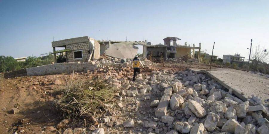 HANDOUT - Ein Mitglied des syrischen Zivilschutzes, bekannt als Weisshelm, steht inmitten von Trümmern von Häusern, die bei einem Luftangriff auf die Provinz Idlib zerstört wurden. Foto: Uncredited/Syrian Civil Defense White Helmets/AP/dpa - ACHTUNG: Nur zur redaktionellen Verwendung und nur mit vollständiger Nennung des vorstehenden Credits