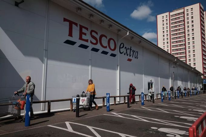 Kunden stehen mit Einkaufswagen und grossem Abstand zueinander in einer Warteschlange des Supermarktes Tesco in London. (Archivbild) Coronavirus - Grossbritannien