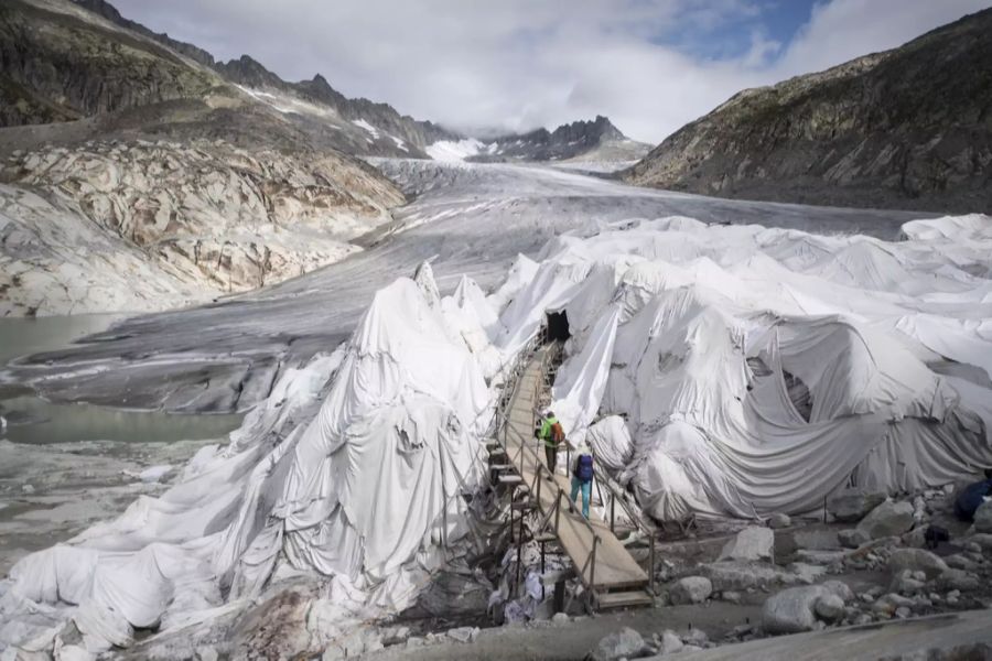 Touristen besuchen die mit Planen abgedeckte Eisgrotte am Gletscherende des Rhonegletscher oberhalb von Gletsch am Furkapass, am Montag, 3. September 2018.