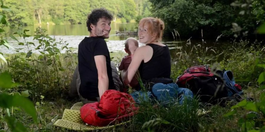 Patrick (l) und Jana Heck bereiten mit ihrem Sohn Tilo in einem Wald bei Trier ihr Nachtlager unter freiem Himmel. Foto: Harald Tittel