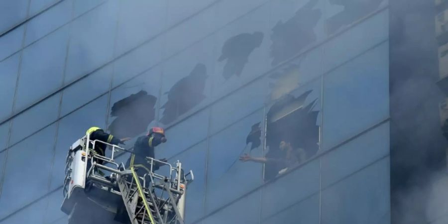Ein Mann steht am Fenster des brennenden Hauses
