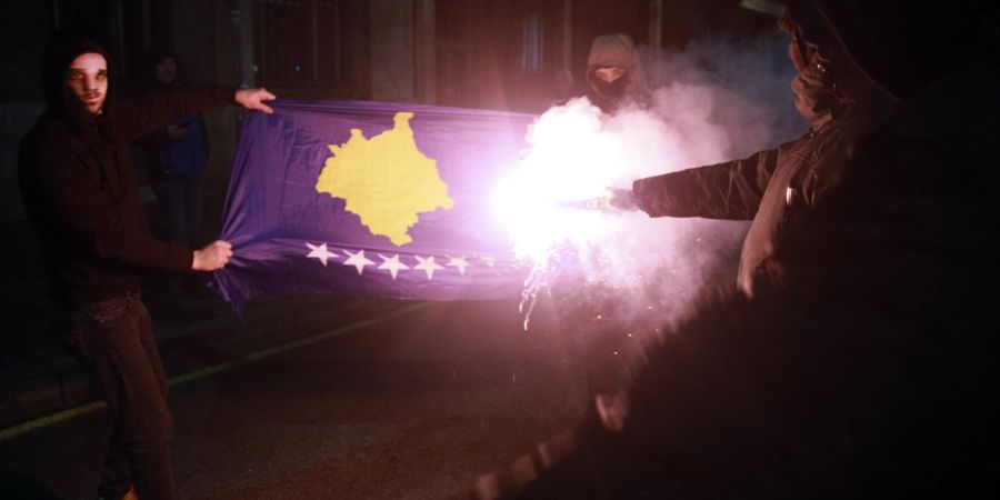 Maskierte Demonstranten zünden eine Kosovo-Fahne in Belgrad an. (AP Photo/Milos Miskov)