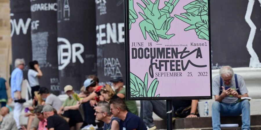 Besucher der documenta fifteen sitzen auf den Stufen des Fridericianums in Kassel.