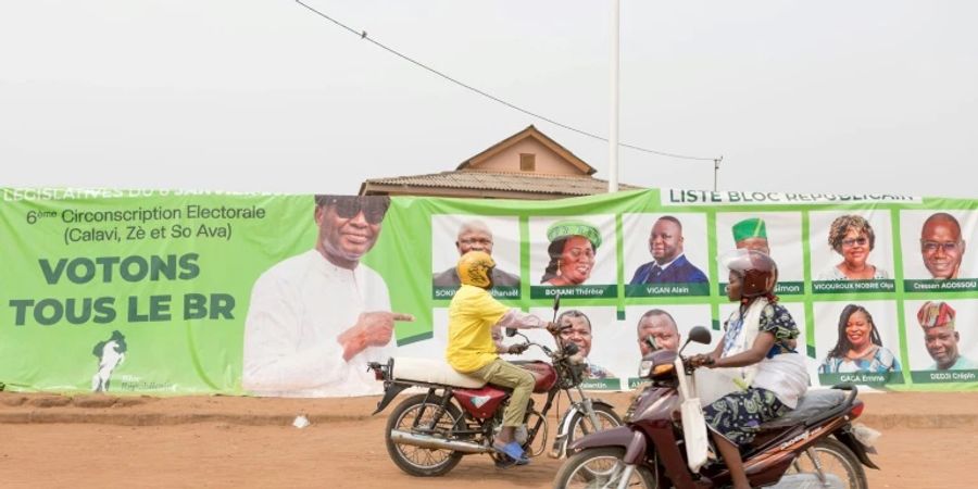 Motorradfahrerin vor Wahlplakat in Benin