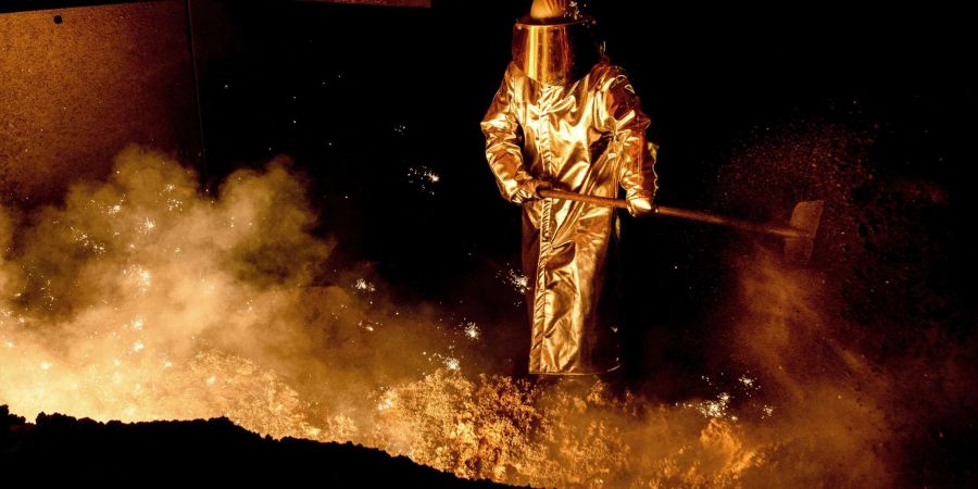 Ein Mitarbeiter schaufelt in einem Stahlwerk Sand in die Abstichrinne am Hochofen. Die Bundesregierung kann der deutschen Stahlindustrie beim Umbruchin eine klimafreundlichere Zukunft helfen.